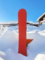Red snowboard standing in snow in ski resort