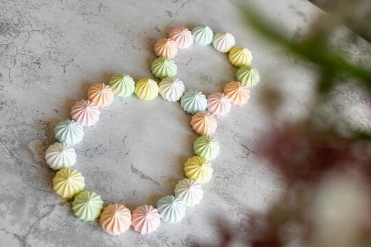 International Women's Day, a holiday for girls, the eighth of March, on the table are sweet colored bize cakes in the form of a number eight, and flowers on a light background, symbolic decorations 
