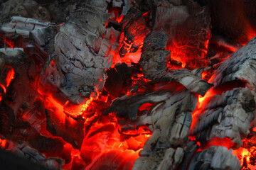 Smoldered logs burned in vivid fire close up. Atmospheric background with flame. Background from a fire, conflagrant firewoods and coals