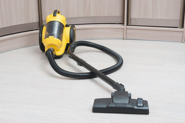 Yellow vacuum cleaner with sweeping brush on a wooden floor