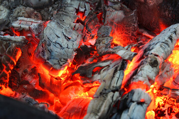 Smoldered logs burned in vivid fire close up. Atmospheric background with flame. Background from a fire, conflagrant firewoods and coals