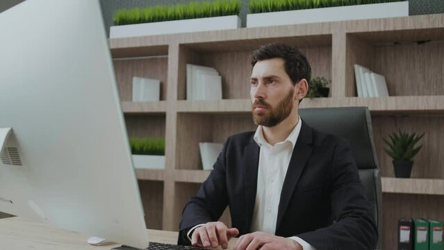 Handsome mature businessman using computer working online sitting in office. typing on the keyboard at workplace