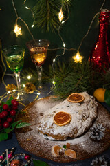 Christmas traditional sweet pastries stollen. Decorated with spruce branches, a garland with lights and glasses of sparkling wine
