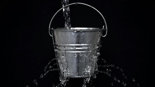 tin bucket with holes on black, slow motion