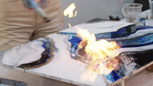 Using a burner to finalize the epoxy resin blue painting