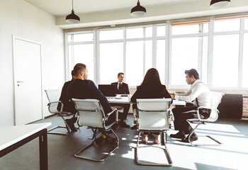 Group of young business people working and communicating while sitting at the office desk together with colleagues sitting. business meeting