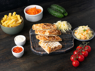 Fototapeta na wymiar Mexican quesadilla with chicken, cucumbers, tomato, pickles and french fries