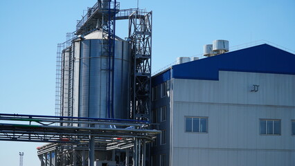 Agricultural Silo - building for storage and drying of grain crops. Industrial concept, silo tower over blue sky. silo tower