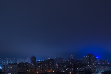 View of the night city in light fog from the top floor of a highrise in Poznyaky, Kyiv, Ukraine.