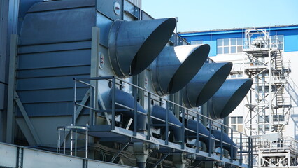Air conditioner units (HVAC) on a roof of industrial building with blue sky and clouds in the...