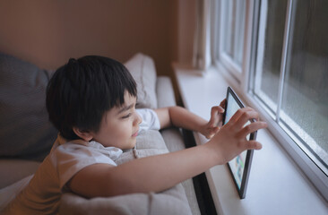 Cinematic portrait a happy young boy playing a game online on the tablet, Kid watching cartoon from...
