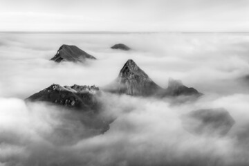 Aerial view of uninhabited volcanic island Ushishir. Island is located in the centre of the Kuril Islands chain. Fog covers volcanic caldera, with the rocks on top