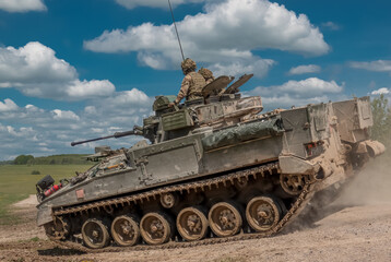 Fototapeta na wymiar British army Warrior FV510 light infantry fighting vehicle tank in action on a military exercise, blue sky with light clouds, Wiltshire UK