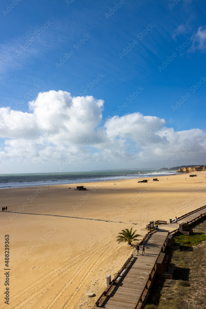 Sticker A vertical shot of the beautiful beach under the blue cloudy sky in Portimao, Portugal