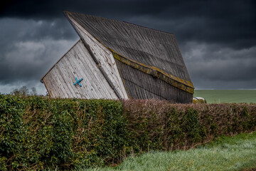 wooden horse stables blown over on to its side strong winds of a storm, thunder storm dark cloud sky
