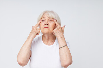 emotional elderly woman in a white t-shirt poor eyesight light background