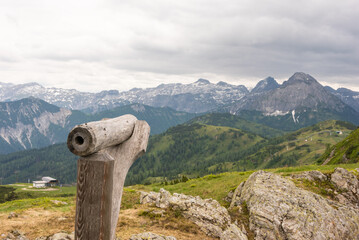 A wooden telescope for observing the top of the mountain. Hiking trail in Austria. In the background, snowy mountains. Flachau - 488242369