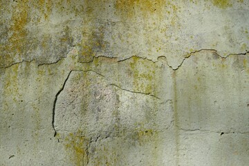 Altes grau-gelbes verwittertes Betonmauerwerk mit Rissen und Ablagerungen bei Sonne im Winter 
