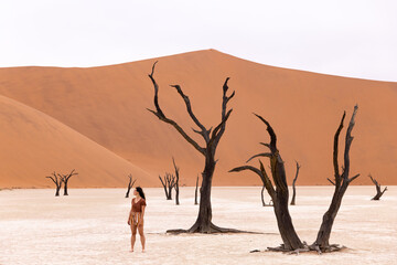 Fototapeta na wymiar Woman walking around sand dunes in Deadvlei Namibia 