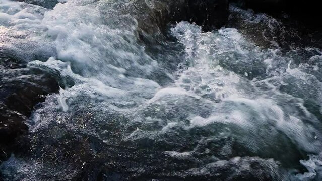 Slow motion of Norwegian mountain river , stream flowing through rocks. Close up of river stones with flowing water, clean water flowing in a mountain river at the Norway