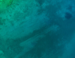 Aerial top view of sea waves hitting rocks on the beach with turquoise sea water. Amazing rock cliff seascape in the Portuguese coastline. Drone shot.