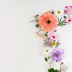 Various flowers composition on flat lay white background. A corner of a frame in a soft light square design.