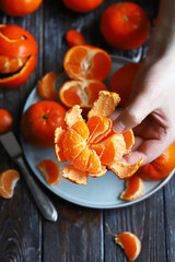 Hands peel the tangerine. Selective focus.