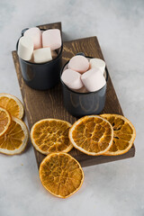 Coffee on wood plate with marshmellow and sliced dry orange