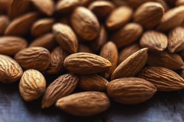 Close up almonds on dark wooden table. Organic health protein vegetarian food. Background copy space