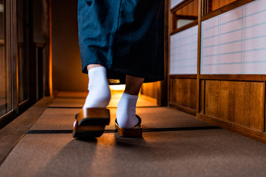 Japanese ryokan machiya traditional house with man in kimono back behind closeup of legs feet with tabi white socks and geta shoes walking by shoji sliding paper door