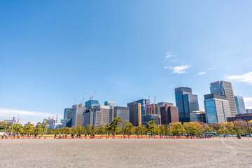 Tokyo, Japan Chiyoda city distant far people walking to Imperial palace park with cityscape skyline skyscrapers construction in downtown district wide angle view blue sky sunny spring day