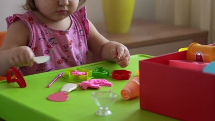 Sculpture and clay modeling for children. Girl 2-5 years old forming and shaping pink play dough by fingers and plastic modeling knife. Enhancing fine motor skills and kid creativity using play clay - Powered by Adobe