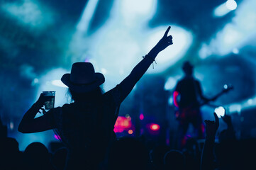 Silhouette of a woman with raised hands on a concert