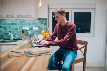 Redhead man working on a laptop in a kitchen at home