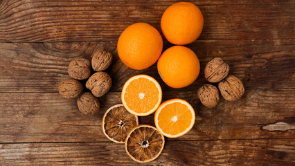 Fototapeta na wymiar Oranges and walnuts on wooden background. Halves and dried oranges. Snack concept, mulled wine addition or autumn pie ingredients. Top view