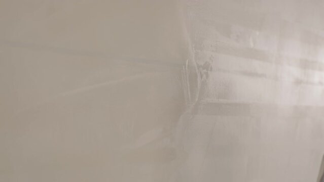 Man plastering the walls with finishing putty in room with putty spatula