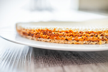 Wafer sheets with filling layers of condensed milk dulce de leche as traditional Ukrainian food cake dessert called Oblatne recipe on white plate closeup macro
