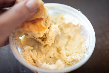 Closeup macro of hand holding baguette bread dipping it into blue crab spread storebought dip with texture detail