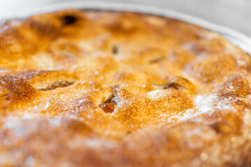 Macro closeup of whole apple pie baked dessert with fruit filling and shape holes in golden crust texture