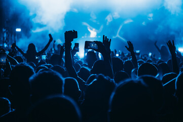 Silhouette of a woman using smartphone on a concert