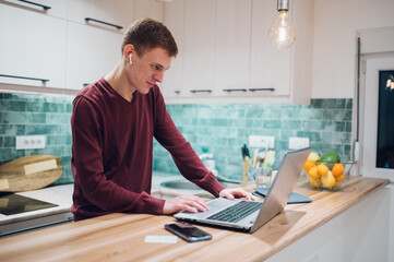 Fototapeta na wymiar Redhead man working on a laptop in a kitchen at home