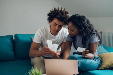 African american couple using a laptop and a credit card while doing finances