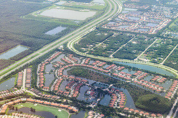 Airplane flying window pov aerial high angle view of residential neighborhood development houses buildings in Fort Myers, Florida USA with Saharan dust pollution