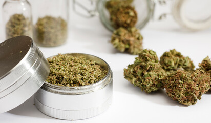 Close up of medical marijuana buds , crusher , glass bottles, white background