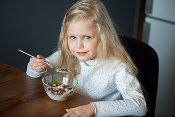 Little girl eating cereal in a bowl of milk