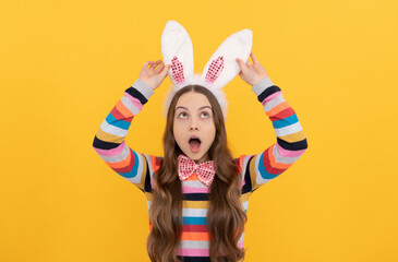amazed easter teen girl in bunny ears and bow tie on yellow background