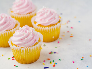 Cupcakes with pink cream isolated on white background with colorful confetti. There is an empty space to insert. Confectionery, recipes for home and restaurant cuisine, culinary blog, recipe book.