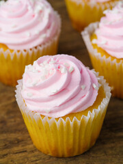 Close-up. Muffins with pink cream on a wooden table. Cooking, supermarket, confectionery, restaurant, hotel, advertising, banner. There are no people in the photo.