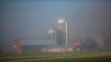 A farm in rural Vermont with red barn and silver silos