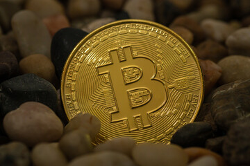 Golden Bitcoin token with Bitcoin Symbol on top of gravel stone. Digital currency. Cryptocurrency